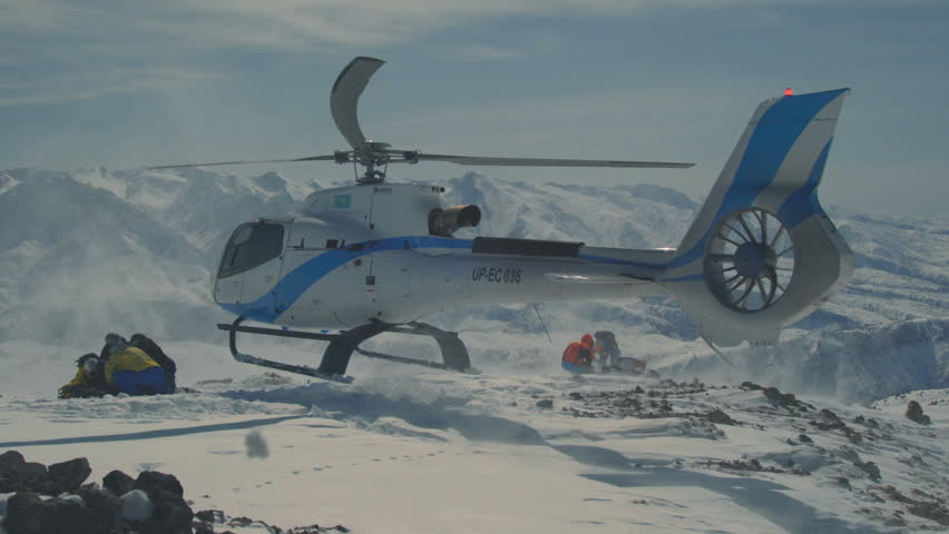 The helicopter left skiers on the slope of the mountain and flew raising a cloud of snow Royalty-Free Stock Footage #1009706735