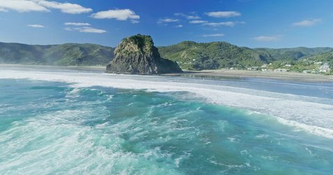 Aerial Over surfers and swimmers in the rough ocean at Piha, Auckland, New Zealand. 2 April 2018