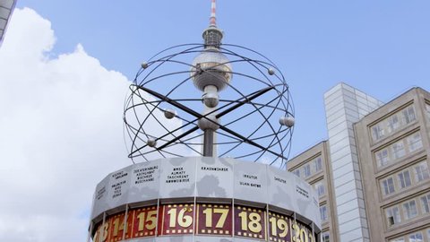 August, 2017 Berlin, Germany, pan from the world time clock at the Alexanderplatz in Berlin to the Berlin television tower with blue sky in the back