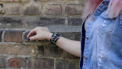 Women's hand with a black leather wristband moving along the brick wall. Slow motion. HD
