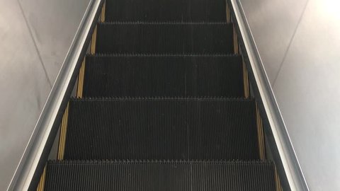 Escalator in the train station is moving down with nobody. An empty steel escalator for modern transportation 