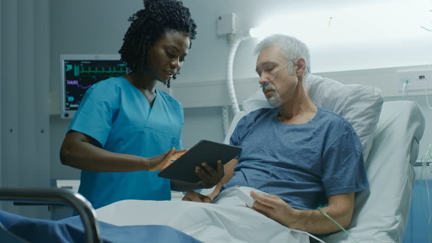 In the Hospital, Senior Patient Lying in the Bed Talking to a Nurse who is Holding Tablet Computer Showing Him Information. In the Technologically Advanced Hospital Ward. Shot on RED EPIC-W 8K Camera. | Shutterstock HD Video #1009728644