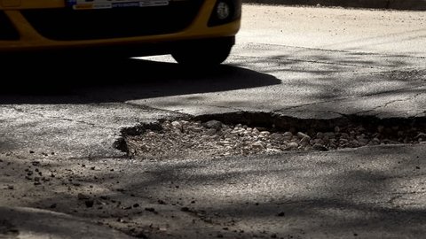 VARNA, BULGARIA: APR 07, 2018 - Cars and cracked asphalt with holes in the road