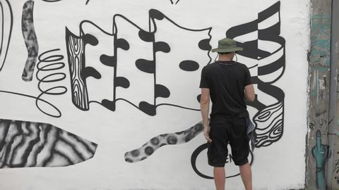 Graffiti artist paint spraying the wall, urban outdoors street art concept. Slow motion Stock Video
