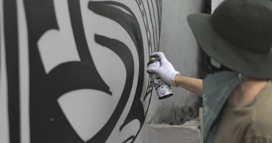 Graffiti artist paint spraying the wall, urban outdoors street art concept. 4k video shooting by handheld gimbal