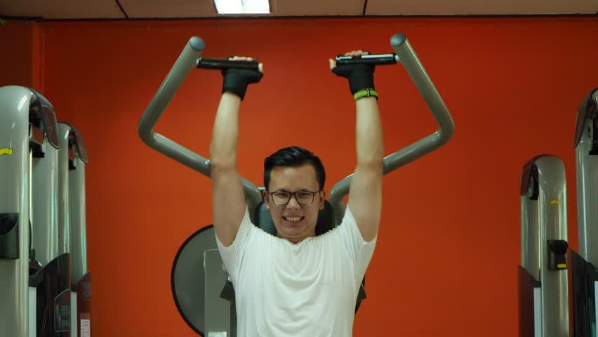 Young Asian man lifting weight in fitness center