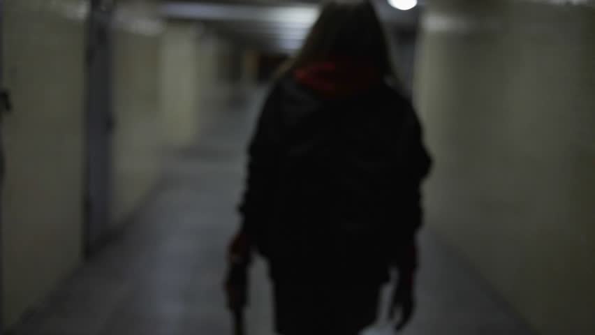 Sporty fashion girl with baseball bat is walking in tunnel