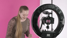 Home video recording studio setup for vlogging. Blogger using ring light panel, digital mirrorless camera and portable background support system. Teenage girl talking about tools for cleaning braces.