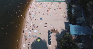 Aerial footage of the beach in Kiev-Ukraine. Flight on the embankment of the hydropark, a large number of people sunbathe under the sun. Summer sunny day, the beach many people rest and bathe. 