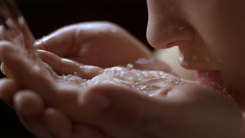 slow motion woman drinking water on her own hands