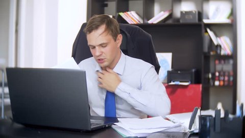 a businessman who scans documents, frowns, using a laptop, does not perform an urgent task in the office, there is not enough time, 4k. the office is hot, the air conditioning is not working