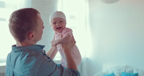 Dad is standing in a room with a little baby in his arms, the kid is smiling Stockvideo