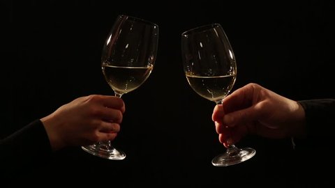 white wine toast, cheers and clinking wine glasses on black background