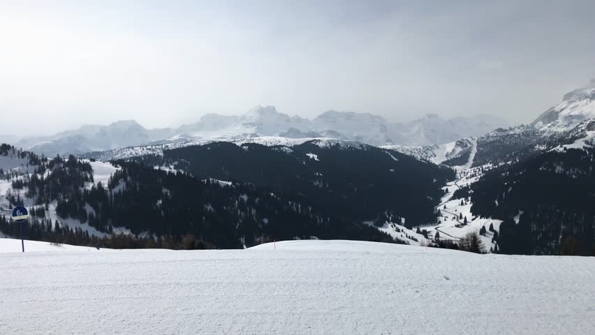 eautiful panoramic view on snowy mountains, ski tracks and a cableway in winter Alps in Italy