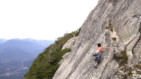 Aerial drone view of active Caucasian American female adventure climber rock climbing Mt Habrich in Squamish Valley Canada Video Stok