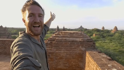 360 degree selfie, man takes a selfie point of view turning 360 degrees with camera. Young man traveller taking selfies on top on ancient Buddhist temple in Bagan Myanmar. 