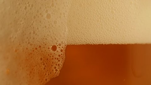 Pouring fresh beer with foam running down, slowmotion footage