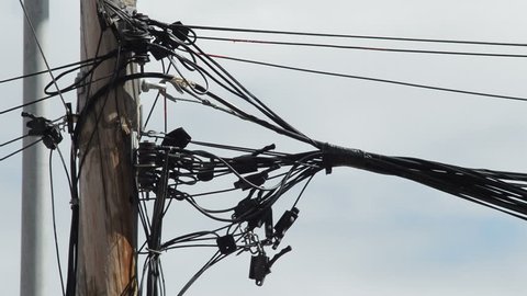Cords wire of different services badly installed on a wooden pole