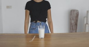 Pretty young woman standing in kitchen drinking oat multy grain milk from glass straw . Zero waste concept. 4k video shooting by handheld gimbal