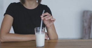 Pretty young woman drinking oat multy grain milk from glass straw . Zero waste concept. 4k video shooting by handheld gimbal