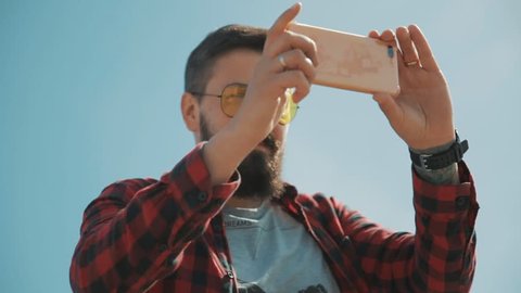 Hipster fashion man with mustache and beard shooting on smartphone 