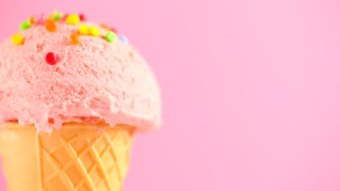 Ice cream cone close-up. Icecream scoop in waffle cone border design rotated over pink color background. Strawberry or raspberry flavor Sweet dessert closeup, Border design, rotation. 4K UHD video 