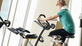 Guy exercises on the bike in the gym on a sunny day
