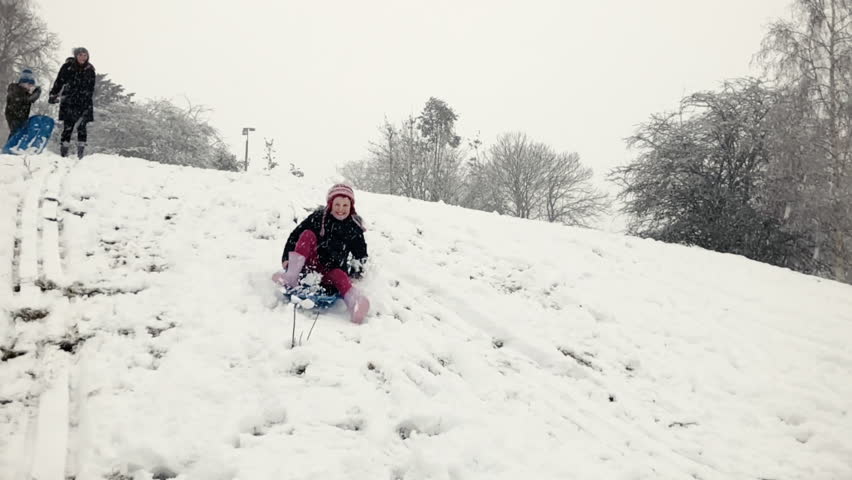 Young girl sledging and coming to a stop
