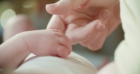 4k ,Parent holding newborns hand in Slow Motion . Happy Family Mother and her Newborn Baby together. Maternity concept. Parenthood. Motherhood. Magic light bokeh background