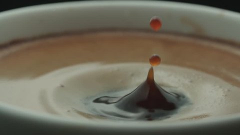 last drop of espresso falls into the filled Cup from the coffee machine in slow motion