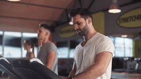 In gym man on a treadmill use phone sportsman sport sunlight fitness internet face technology fit male smile workout athlete sportswear body exercise healthy mobile smartphone young slow motion