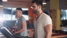 Attractive man on a treadmill in gym use phone sportsman sport fitness internet face technology fit male smile workout athlete sportswear body exercise healthy mobile smartphone young slow motion