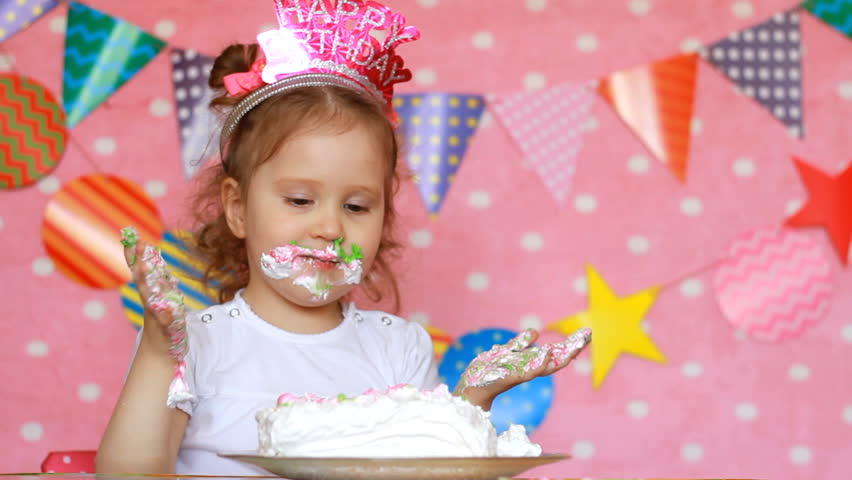 Happy birthday. Party. Funny child eats cake and gets dirty face and hands. Cute girl licks her fingers with dessert. Royalty-Free Stock Footage #1009804556