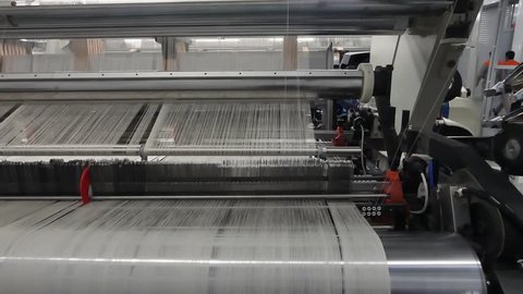 weaving loom at a textile factory, closeup. industrial fabric production line. the camera is stationary