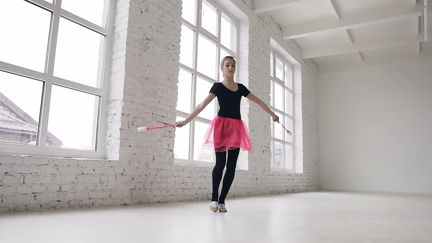 Cute blonde hair girl doing exercive with mace in the hand in the studio on white background near big windows and smiling on camera. View from the bottom, slow motion