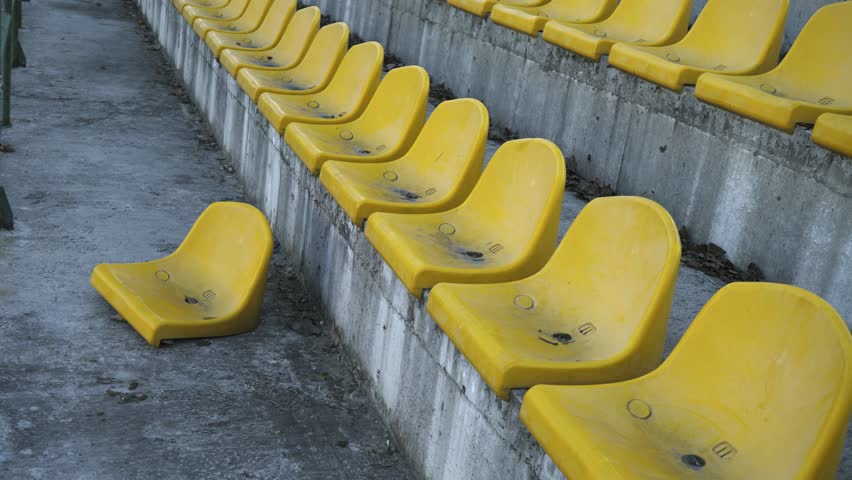 Yellow chairs in an empty stadium. Canceled match, game. An empty stadium without fans. Spectators were not allowed into the stadium. 4k
