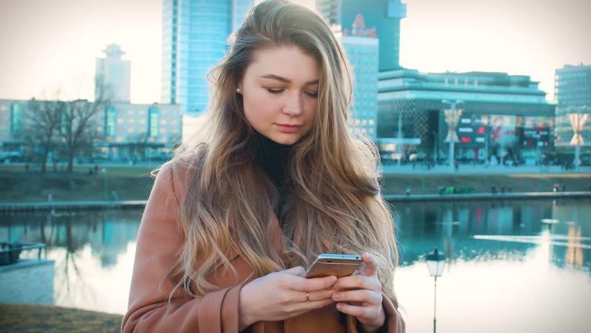 Young girl reads message from phone on background of big city
