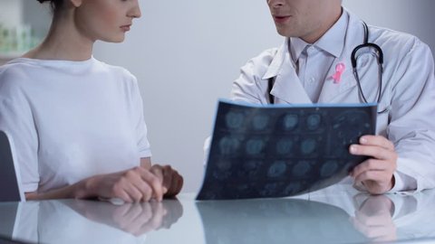 Oncologist informing woman about no threat of breast cancer, both smiling