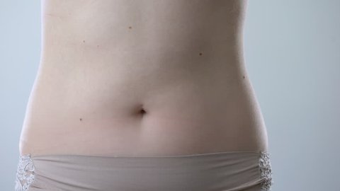 Surgeon drawing marks on abdomen, preparing woman for liposuction surgery