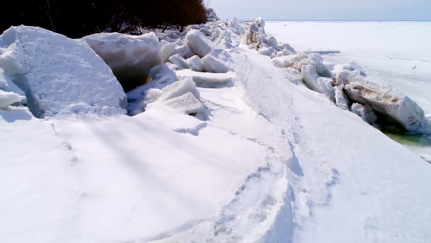 Low aerial flight over scenic, surreal jagged ice shoves on the shore of Door County Wisconsin; created by high winds in Springtime which heaves and cracks the thick ice on the rocky shores.