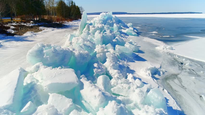Low aerial flight over scenic, surreal jagged ice shoves on the shore of Door County Wisconsin; created by high winds in Springtime which heaves and cracks the thick ice on the rocky shores.