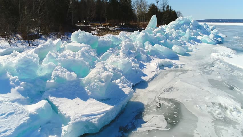 Low aerial flight over scenic, surreal jagged ice shoves on the shore of Door County Wisconsin; created by high winds in Springtime which heaves and cracks the thick ice on the rocky shores.