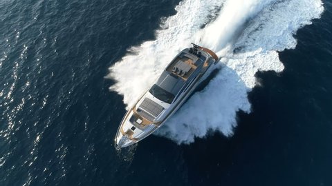 Aerial perpendicular view of a luxury yacht navigating fast.