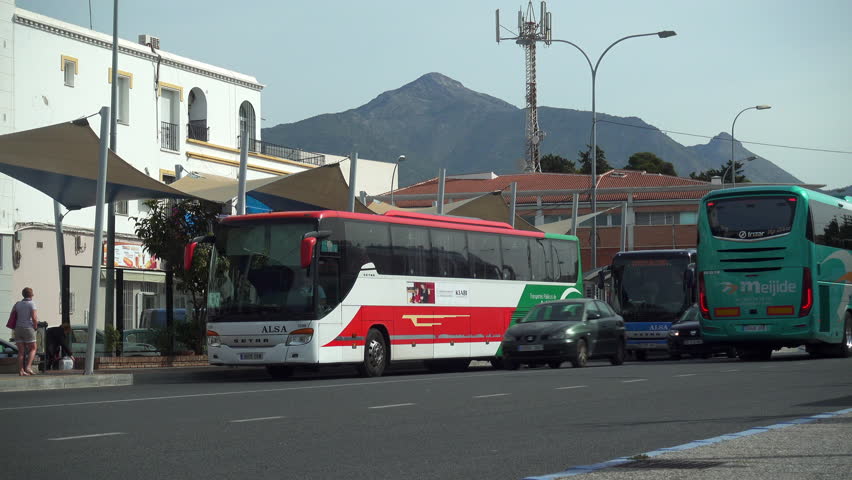 Nerja, Costa del Sol, Andalusia, Spain - March 29, 2018: Road traffic passing through the bus station as a bus waits for passengers at Nerja on the Costa del Sol in Spain.
