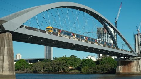 Brisbane - March 2018: Train on railway bridge and fast ferry passing by. 4K resolution.