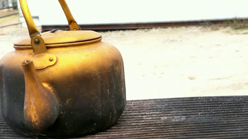 Yellow metal kettle boils water on the grill. 4k