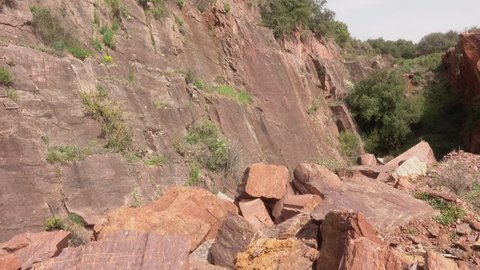 senior couple climbs over the piled stones of red marble in the mountains.