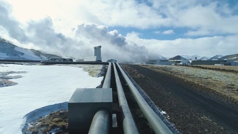 Pipes leading to Geothermal Power Plant. Steam are generated in the background. Snowy environment 