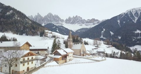 Aerial drone view of famous Santa Maddalena mountain village in the Dolomites with snowy Gruppo delle Odle mountain range in the background in winter, Val di Funes, South Tyrol, Italy, Europe