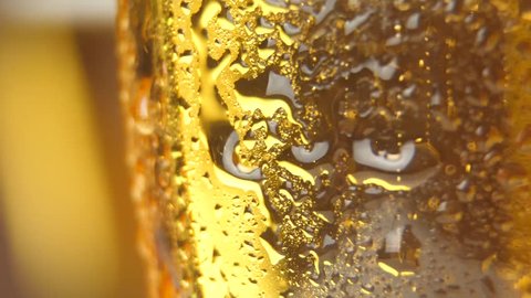 cold light beer with bubbles in a glass and dripping condensate drops